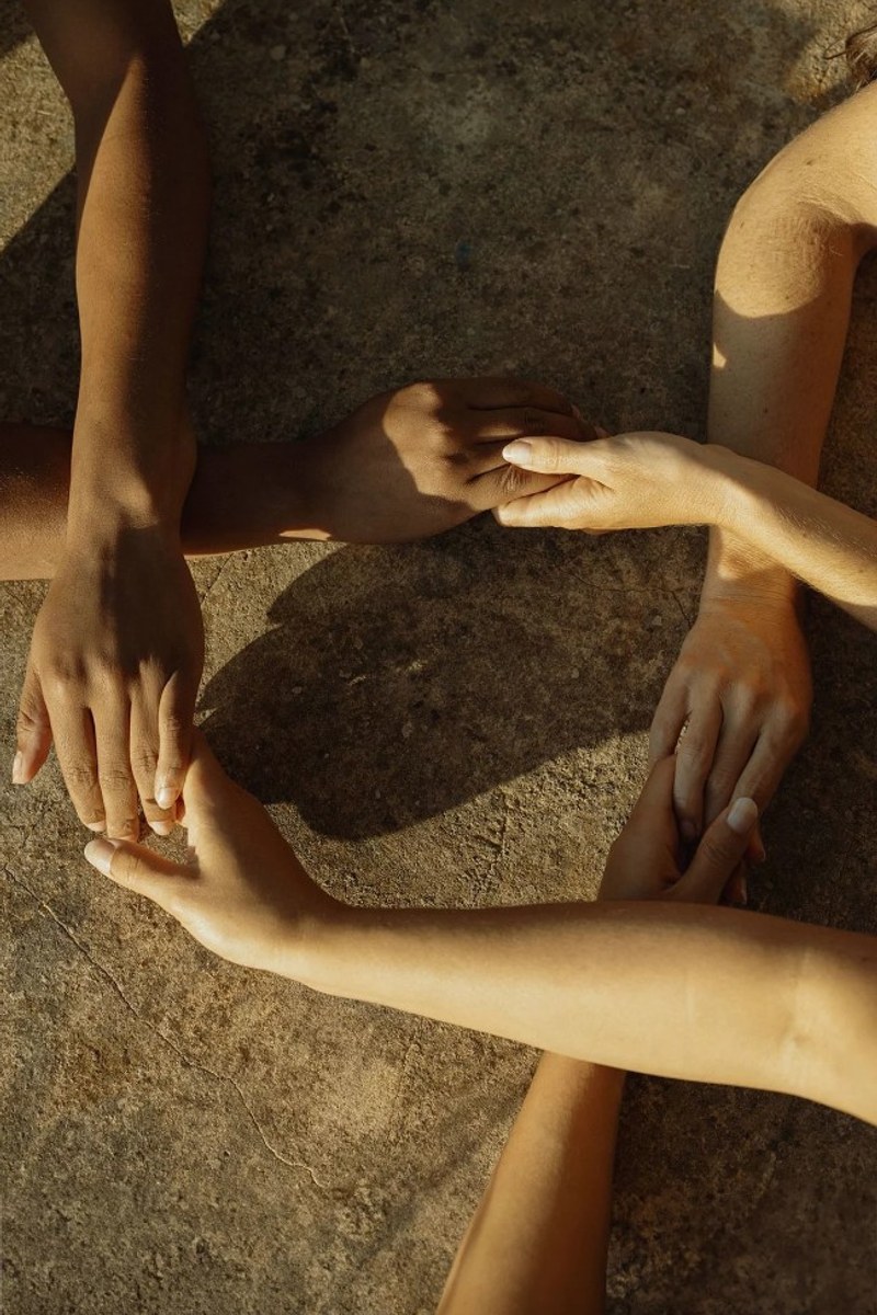 Four people holding hands together in a circle, seen from above